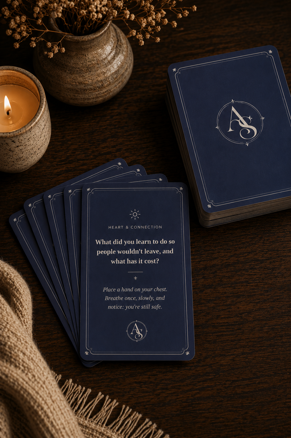The Deepening Set — navy blue cards fanned out beside a candle