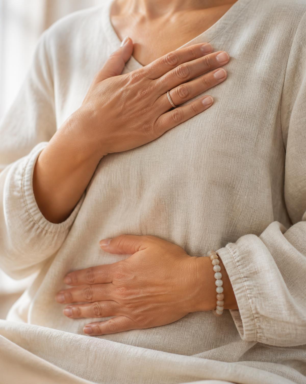 A person resting one hand on their chest and one on their belly during a breathing practice